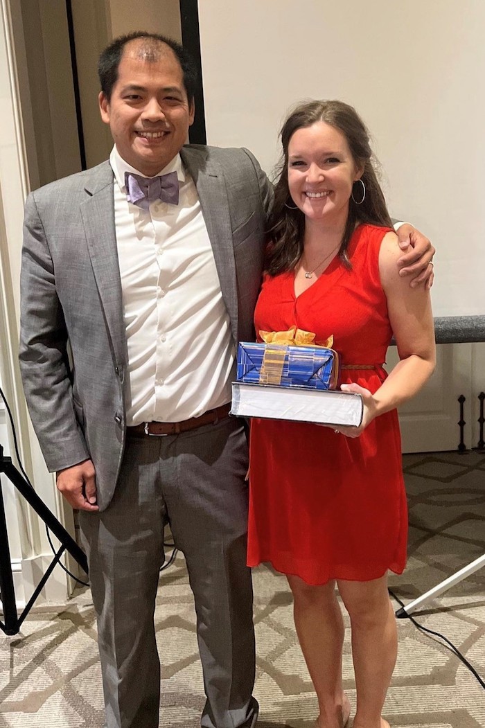 Two Department of Ophthalmology fellows posing as one holds an award.